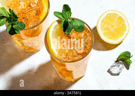 Long Island Ice Tea Cocktail Drink. Zwei Gläser Eistee mit Zitronenscheiben, Minze und Eis auf weißem Hintergrund, trendiges hartes Licht mit Schatten. Homem Stockfoto