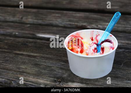 Eis mit einem Löffel in einem Pappbecher auf einer Bank Stockfoto