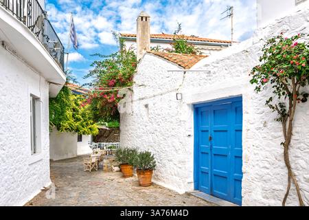 Eine malerische Straße mit weiß getünchten Häusern und einem Straßencafé im Dorf der kleinen griechischen Insel Hydra, Griechenland. Stockfoto
