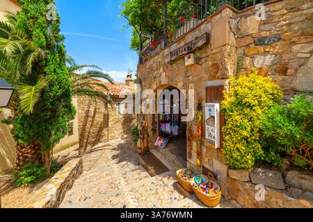 Eine enge Kopfsteinpflasterallee mit Geschäften und Cafés im Schloss Murallas de Tossa de Mar aus dem 12. Jahrhundert im Dorf Tossa de Mar, Spanien, Costa Brava Stockfoto