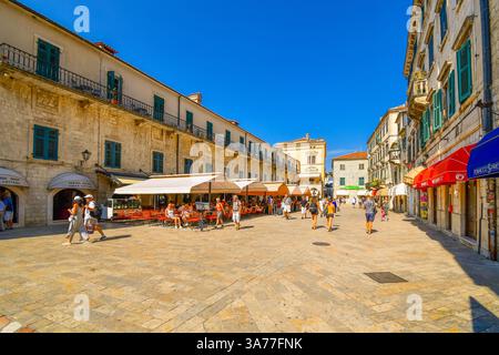 Touristen besichtigen, essen Sie in Straßencafés und kaufen Sie auf dem Platz des Wappens in der mittelalterlichen, von Mauern umgebenen Altstadt von Kotor, Montenegro Stockfoto