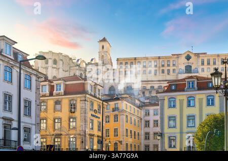 Blick auf den frühen Sonnenuntergang auf das Kloster Carmo oder das Kloster unserer Lieben Frau von Karmel und den Uhrturm vom Rossio-Platz im historischen Zentrum von Lissabon, Portugal Stockfoto
