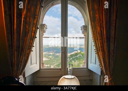 Blick aus einem Fenster auf den Pena-Palast auf die auf einem Hügel gelegene maurische Burg in Sintra Portugal. Stockfoto