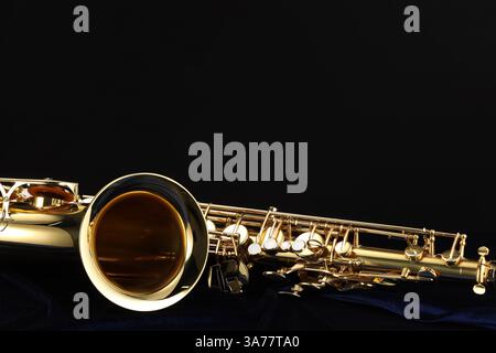 Jazz. Ein wunderschönes Saxophon auf dunkelblauem Stoff vor schwarzem Hintergrund, Nahaufnahme. Leerzeichen für Text Stockfoto