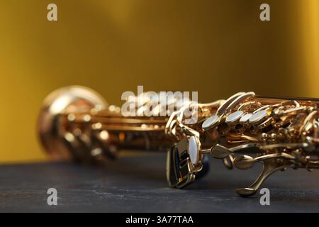Jazz. Ein schönes Saxophon auf schwarzem Tisch vor farbigem Hintergrund, Nahaufnahme Stockfoto
