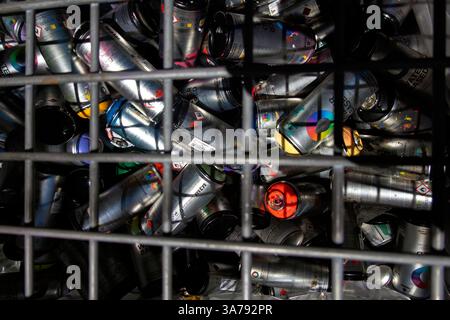 Entsorgung gebrauchter Sprühdosen hinter Gittern Stockfoto