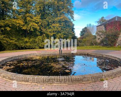 Reflektierender Teich mit Bronzestatue in einem Landschaftsgarten im Herbst in Schottland. Stockfoto