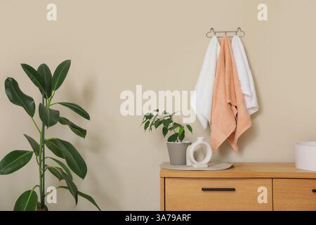 Saubere Handtücher hängen an der beigefarbenen Wand neben dem modernen Waschbecken im Badezimmer Stockfoto