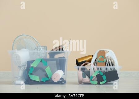 Behälter mit Elektronikschrott zum Recycling in der Nähe beiger Wände Stockfoto