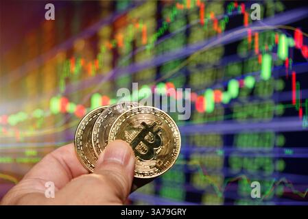 Bitcoin-Goldmünze in der Hand und defokussierter Kartenhintergrund. Bitcoin-Konzept, Blockchain-Technologie, Kryptowährung, virtuelles Geld. Stockfoto
