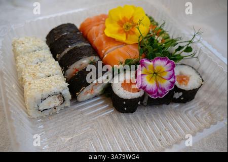 Mischung aus Sushi-Brötchen mit Lachs, Avocado, geräuchertem Aal in einer Lebensmittelverpackung aus Kunststoff. Stockfoto