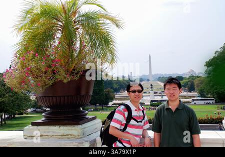 Touristen posieren für Fotos mit dem Washington Monument in der National Mall in der Ferne. Washington D.C. Stockfoto