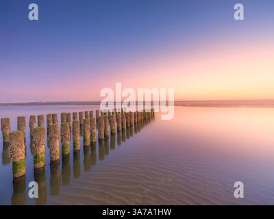 Sonnenuntergang an einem wunderschönen Abend am Strand mit farbenfrohem Himmel und goldenem Sonnenlicht in Zeeland, Niederlande Stockfoto