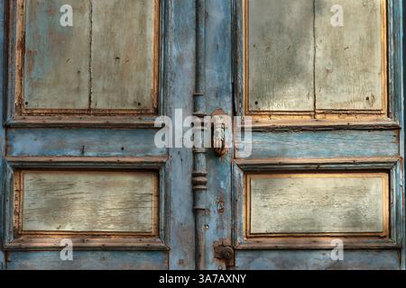 Eine alte blaue Tür mit einem verwitterten Metallklopfer. Stockfoto