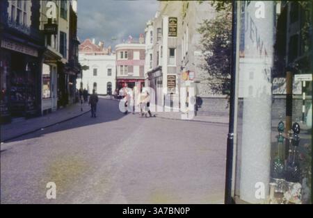 Ein offener Blick auf die Portobello Road in London, aufgenommen in den 1960er Jahren Dieses originale 35-mm-Filmfoto zeigt Fußgänger, die an klassischen Geschäften vorbeischlendern, darunter „The Pipe Shop“, und spiegelt den lebhaften Charakter dieses berühmten Londoner Ortes wider. Stockfoto
