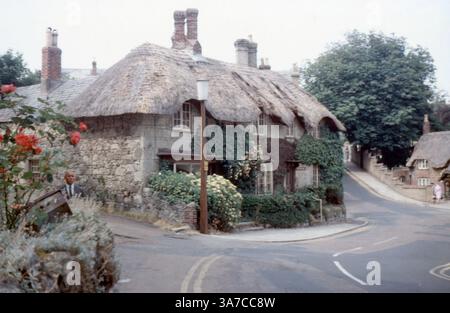 Eine zeitlose Dorfszene aus den 1960er Jahren in Shanklin, Isle of Wight, mit einem bezaubernden strohgedeckten Häuschen an einer geschwungenen Straßenecke. Stockfoto