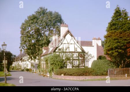 Eine friedliche Szene aus den 1960er Jahren entlang der Tavern Lane in Shottery, Stratford-upon-Avon, Warwickshire. Traditionelle Fachwerkhäuser mit blühenden Gärten säumen die ruhige Straße, die charakteristisch für die historische Dorfatmosphäre und den Shakespeare-Charme der Gegend ist. Stockfoto