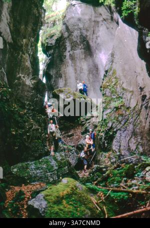 Eine Gruppe abenteuerlustiger Wanderer navigiert vorsichtig auf dem felsigen Pfad durch die dramatische Giffre-Schlucht in der Nähe von Sixt-Fer-à-Cheval, Frankreich. Stockfoto