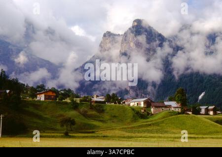 Ein nebeliger Morgen im Bergdorf Sixt-Fer-à-Cheval, Frankreich, im Juli 1972. Eingebettet am Fuße dramatischer Kalksteingipfel, liegt dieses malerische Dorf inmitten üppiger grüner Weiden und steiler Berghänge, mit Wolken, die in einer ruhigen und zeitlosen Szene durch das Tal treiben. Stockfoto