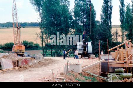 Eine Baustelle in einem ländlichen Gebiet im Sommer 1977, auf der Arbeiter und schwere Maschinen einschließlich Kräne und Bagger gezeigt werden. Stockfoto