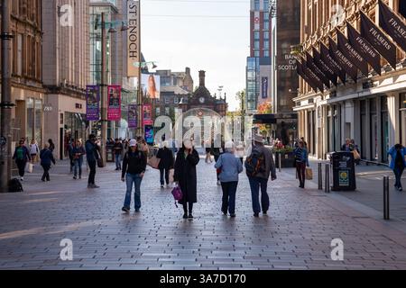Geschäftige Buchanan Street im Stadtzentrum von Glasgow mit Fußgängern, modernen Geschäften, Bannern und dem Eingang zur U-Bahn-Station St. Enoch. Stockfoto