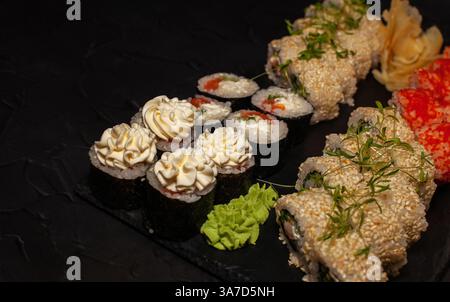 Japanisches Sushi auf einem schwarzen Teller mit Wasabi und Ingwer Stockfoto
