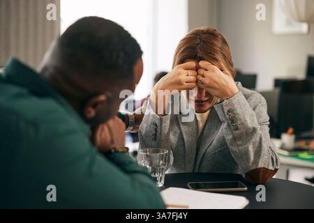 Männlicher Geschäftsmann tröstet weinende Kollegin im Amt Stockfoto