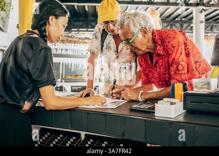Senior Mann unterschreibt Papier beim Einchecken in der Ferienwohnung mit Freund Stockfoto