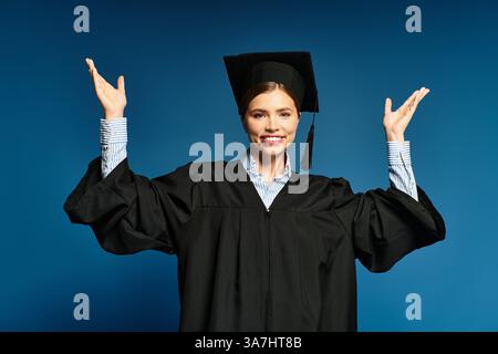 Die junge Frau drückt ihr Glück aus, während sie ihren Abschluss in einem stilvollen Mütze und Kleid feiert. Stockfoto