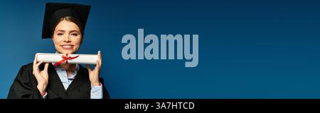Eine junge Frau in Abschlussbekleidung strahlt vor Stolz und hält ihr Diplom. Stockfoto