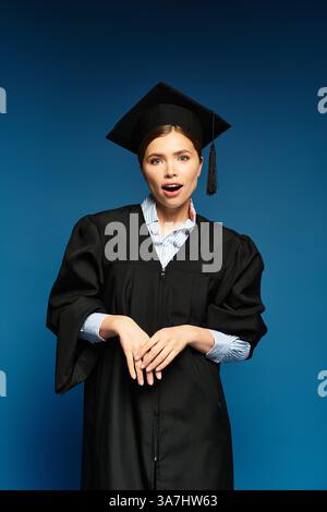 Eine junge, schöne Frau strahlt Begeisterung in ihrer Abschlusskleidung aus und feiert stolz den Erfolg. Stockfoto