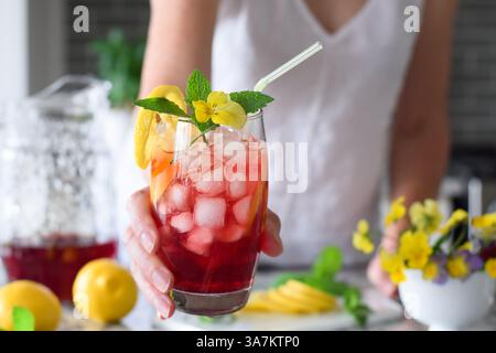 Die Frau greift mit einem farbenfrohen roten, kalten Sommergetränk rein Stockfoto