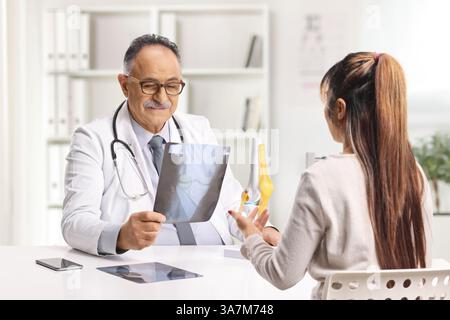Junge Patientin und Ärztin diskutieren ein Röntgenbild in der Arztpraxis Stockfoto