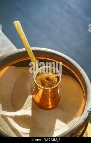 Türkischer Kaffee in einem Cezve auf dem Sand zubereiten, frisches Kaffeegetränk Stockfoto