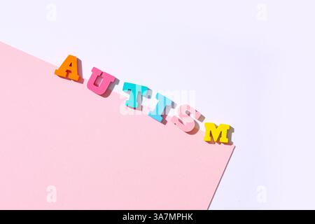 WORTAUTISMUS aus bunten Buchstaben und rosa Papierbogen auf hellem Hintergrund Stockfoto