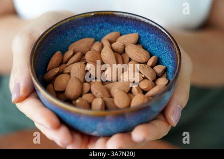 Mandeln Ungeschält. Nahaufnahme von weiblichen Händen, die eine Schüssel voller Mandeln ohne Schale halten. Stockfoto