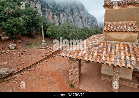 Aus der Vogelperspektive auf die Ermita de Sant Miquel Eremitage in der Nähe der Abtei Montserrat in Katalonien, Spanien, an einem nebligen bewölkten Tag mit dramatischer Berglandschaft Stockfoto
