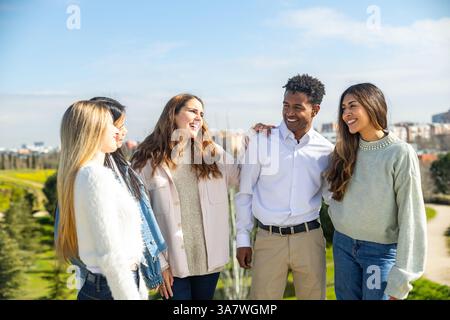 Eine Gruppe fröhlicher junger, multiethnischer Kollegen, die einen entspannten Tag in einem Park genießen, Lachen und gute Zeiten teilen Stockfoto