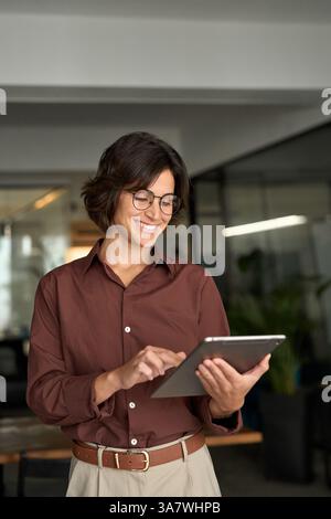Lächelnde, beschäftigte Geschäftsführerin mit Tablet im Büro. Stockfoto