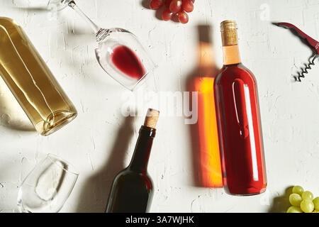 Draufsicht Anordnung feiner Rot- und Weißweine liegend Auf gesprungener Oberfläche inmitten von Weinreben und Weintrauben Stockfoto