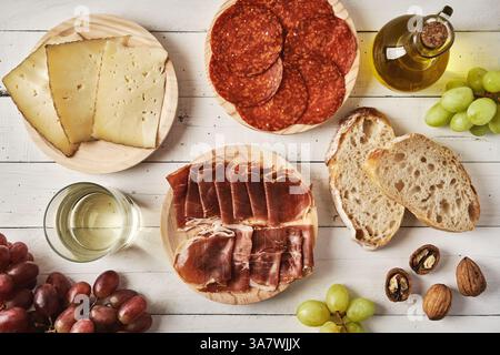 Draufsicht Anordnung der Teller mit appetitlich geschnittener Wurst und Käse wird auf einem Plankentisch neben süßen Trauben und Brot serviert Stockfoto