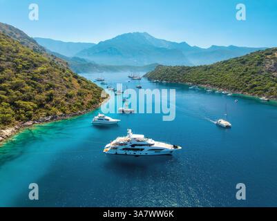 Blick aus der Vogelperspektive auf wunderschöne Yachten und Boote auf dem Meer bei Sonnenuntergang im Sommer. Gemiler Island in der Türkei. Blick von oben auf Luxusyachten, Segelboote, klares Blau mit Stockfoto