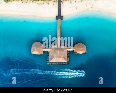 Blick aus der Vogelperspektive auf den Bungalow, Boot im blauen Meer bei Sonnenuntergang im Sommer. Restaurant am Meer. Blick von der Drone auf das hölzerne Hotel, azurblaues Wasser, weißer Sandstrand Stockfoto