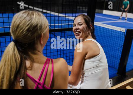 Frauen mögen Padel-Tennis-Matches, lächeln und plaudern am Spielfeld Stockfoto