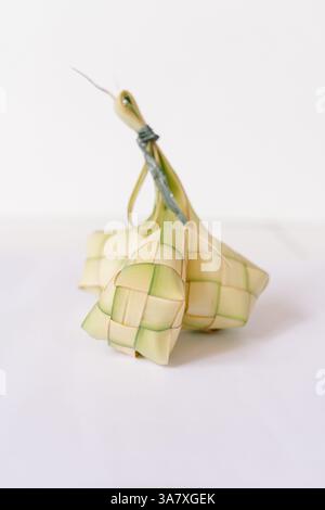 Ketupat, traditioneller Reisknödel, serviert während Eid al-Fitr. Gekochter Reis wird in einem diamantförmigen Behälter aus gewebtem Palmblattbeutel verpackt. Isolat Stockfoto