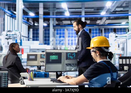 Industrielle Automatisierungstechniker in Solarpaneelanlagen, die Robotermaschineneinstellungen mithilfe von Computersoftware anpassen. Mitarbeiter der Photovoltaik-Fabrik diagnostiziert Leistungsprobleme Stockfoto