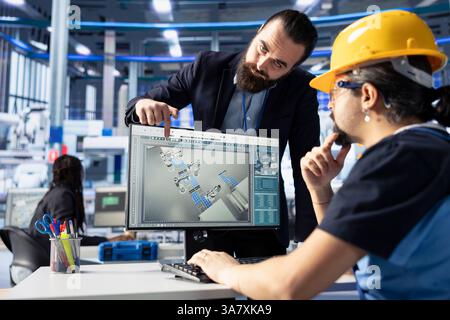 Supervisor in der Photovoltaik-Fabrik, der den Techniker beaufsichtigt, die Systemprotokolle zu überprüfen, um betriebliche Ineffizienzen zu identifizieren. Teamleiter und Spezialist für Photovoltaikanlagen, die Fertigungsparameter anpassen Stockfoto