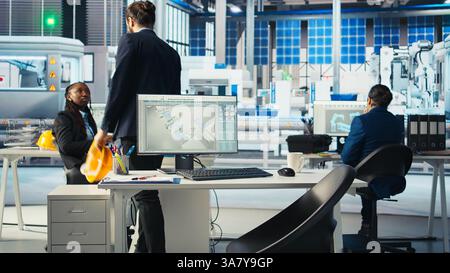 Manager, der bei der Arbeit in der Photovoltaik-Fabrik ankommt, Daten analysiert, Systemkennzahlen überprüft. Mann in umweltfreundlichen Solarpaneelen, die erneuerbare Energien produzieren, Fehlerbehebung bei technischen Problemen Stockfoto