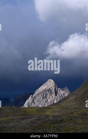 Sonnendurchfluteter Berg mit Sturmwolken im Hintergrund. Der Ausangate Berg in der Vilcanota Bergkette. Pacchanta, Cusco, Peru Stockfoto