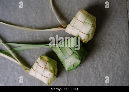 Nahaufnahme von Three Ketupat, einem traditionellen Reisknödel, der in Südostasien besonders während der Eid al-Fitr-Feierlichkeiten beliebt ist. Diese gewebte Palme lea Stockfoto